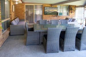 eine Außenterrasse mit einem Glastisch und Stühlen in der Unterkunft Serene Saltair in Redland Bay