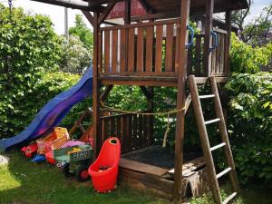 ein hölzerner Spielturm mit einem Spielplatz im Gras in der Unterkunft Familienfreundliche Gemütliche Ferienwohnung In Luchau Mit Garten Und Grill - in Glashütte