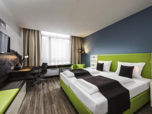 a bedroom with a green and white bed and a desk at ibis Styles Offenburg City in Offenburg
