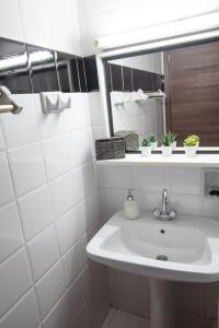 une salle de bain blanche avec un lavabo et un miroir dans l'établissement Snow Chalets Parnassos Arachova's Nest, à Arachova