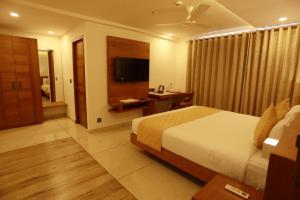 una habitación de hotel con una cama y un televisor en Devalokam Grand, en Edappāl