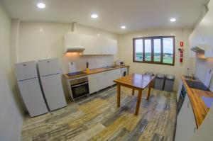 cocina con electrodomésticos blancos y mesa de madera en Camping Playa de Ajo, en Ajo