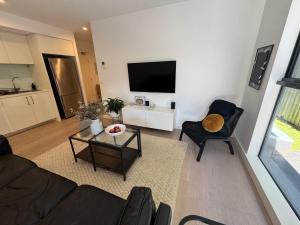 ein Wohnzimmer mit Sofa, Sesseln und Fernseher in der Unterkunft Beautiful light filled modern apartment in Kew in Melbourne