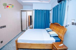 a bedroom with a bed with blue curtains and a bed sidx sidx sidx at Les HOTES de DALEA in Ouagadougou
