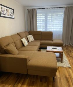 a living room with a brown couch and a table at Apartament Wysoka Brama in Lidzbark Warmiński