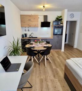 a kitchen and living room with a table and a laptop at Pfalz Studio in Speyer - stilvoll, modern & zentral in Speyer