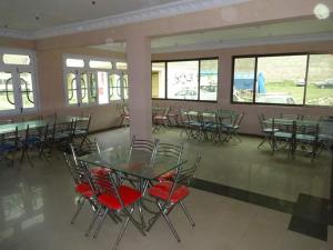 a dining room with tables and chairs and windows at Pinehills Hotel in Dargai