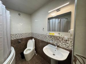 a bathroom with a sink and a toilet and a mirror at The Artist Regency Hotel Tashkent in Toshkent-Passajir Bekati