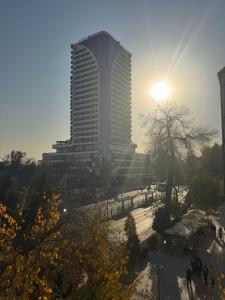 a tall building with the sun in the background at The Artist Regency Hotel Tashkent in Toshkent-Passajir Bekati