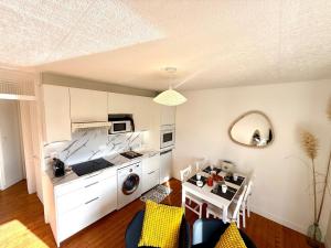 Le Wim Break, Centre et Mer à 2 pas في ويميريوكس: مطبخ مع دواليب بيضاء وطاولة مع كراسي