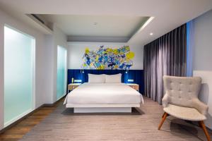 ein Schlafzimmer mit einem weißen Bett und einem Stuhl in der Unterkunft Yello Hotel Jambi in Jambi + 32 Fotos