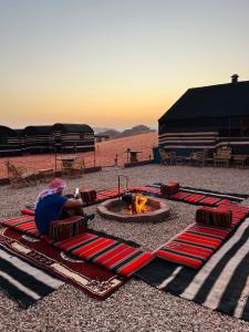 瓦迪拉姆Desert Key Camp的一个人坐在火坑旁的毯子上