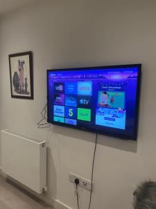 a flat screen tv hanging on a wall at Your Private Apartment in Vibrant Wembley! in London