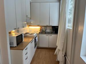 une petite cuisine avec des armoires blanches et un micro-ondes dans l'établissement Kotimaailma - Tilava kaksio Kotkan Rauhalassa, à Kotka