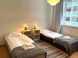 deux lits jumeaux dans une chambre avec fenêtre dans l'établissement Kotimaailma - Tilava kaksio Kotkan Rauhalassa, à Kotka