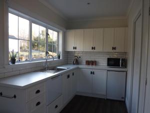 a kitchen with white cabinets and a sink and a window at Karetu Downs Farm Stay in Hawarden