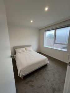 une chambre blanche avec un lit et une fenêtre dans l'établissement Private Cozy Flat in A Spacious Flat in Carnegie, à Carnegie