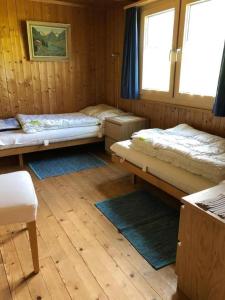 une chambre avec trois lits et une fenêtre dans l'établissement Neuer Sigerst, à Wildhaus