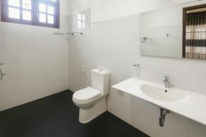 a white bathroom with a toilet and a sink at Comfy Stay in Badulla