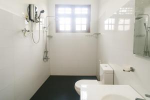 a white bathroom with a toilet and a window at Comfy Stay in Badulla +5 photos