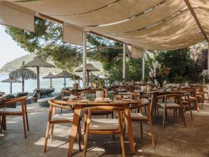 ein Restaurant mit Tischen und Stühlen und Blick auf das Meer in der Unterkunft Four Seasons Resort Mallorca at Formentor in Port de Pollença