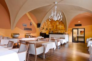 バンスカー・ビストリツァにあるHotel Arcadeの白いテーブルと椅子、シャンデリアのあるレストラン