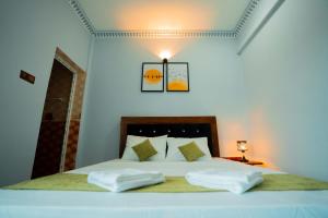 a bedroom with a white bed with two pillows at Best Inn in Jaffna