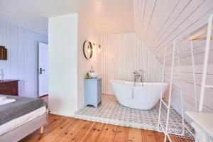 a white bathroom with a tub and a bed at Altes Fährhaus - Ferienwohnung Boven, 220 qm in Wewelsfleth