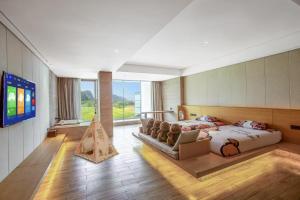 une chambre avec un lit, un canapé et une télévision dans l'établissement Yangshuo County Rice Field Resort Hotel, à Yangshuo