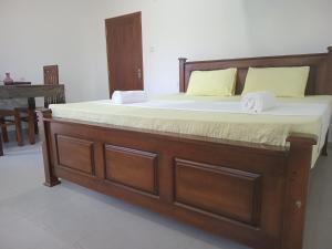 un letto con struttura in legno e due asciugamani di Mihinsa Guest a Kosgoda