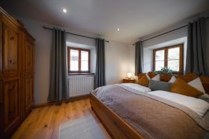 a bedroom with a large bed and two windows at Natur Hof Schwarnlehen in Berchtesgaden