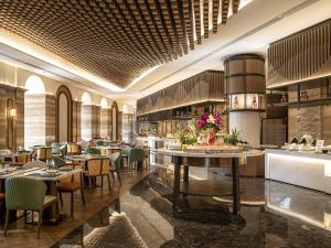 ein Restaurant mit Tischen und Stühlen in einem Raum in der Unterkunft Pullman Haikou in Haikou