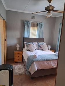 a bedroom with a bed with blue curtains and a fan at Susanna's Self catering 2 bedroom apartment in Kimberley