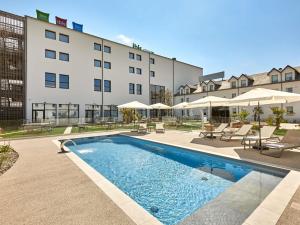 ein Hotel mit einem Swimmingpool vor einem Gebäude in der Unterkunft ibis Styles La Roche-sur-Yon in Mouilleron-le-Captif