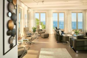 ein Wohnzimmer mit Sofas und Stühlen und Fenstern in der Unterkunft Appartement in Sellin mit Garten, Sauna und Terrasse und Meerblick in Ostseebad Sellin + 32 Fotos