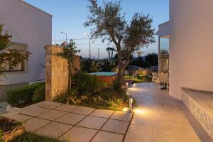 einen Garten mit einer Terrasse mit einem Baum und einem Haus in der Unterkunft The Twin Boutique Hotel in Torre Suda