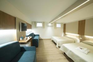 ein Hotelzimmer mit 2 Betten und einem blauen Sofa in der Unterkunft The Twin Boutique Hotel in Torre Suda