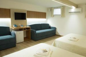 Zimmer mit 2 Betten, einem Sofa und einem TV in der Unterkunft The Twin Boutique Hotel in Torre Suda