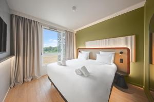 un grand lit blanc dans une chambre avec une fenêtre dans l'établissement Campanile PRIME - Smart Lyon Chaponost, à Chaponost 34 autres photos
