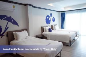 a hotel room with two beds and an umbrella on the wall at Kokotel Phuket Patong in Patong Beach