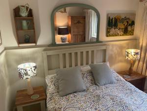 Un dormitorio con una cama con dos lámparas y un espejo. en Crispins Corner, en Stedham