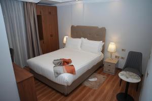 a bedroom with a bed and a chair and a table at Yofel Hotel Bole in Addis Ababa