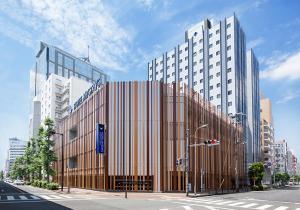 een hoog gebouw in een stadsstraat met een verkeerslicht bij HOTEL MYSTAYS Shin Osaka Conference Center in Osaka