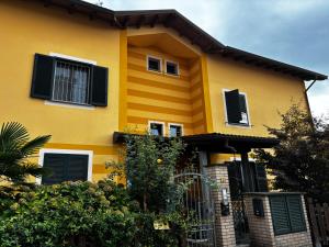 ein gelbes Haus mit schwarzen Rollläden darauf in der Unterkunft Ulisse Fashion Suites - Ecosole Real Estate in Serravalle Scrivia