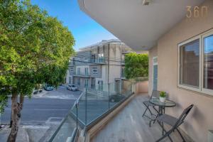Un balcón con una mesa y sillas y una calle. en Beautiful 3BR homes with comfy beds, WIFI & AC by 360 Estates, en Naxxar