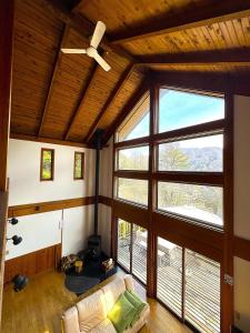Cabin B vacation house rental Mt Fuji View 3 min lake Saiko 5min drive Lake Kawaguchi في فوجيكاواجوتشيكو: غرفة معيشة مع مروحة سقف ونوافذ كبيرة