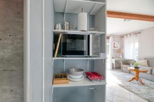 a kitchen with a microwave and a living room at Chez Anne Marie Et Daniel in Gardouch