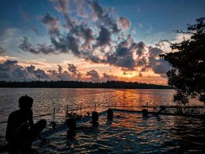 eine Gruppe von Menschen im Wasser bei Sonnenuntergang in der Unterkunft IslandOnBolgoda in Piliyandala + 1 Foto