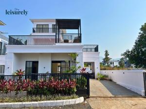 Stay Leisurely Casa Astre 3BHK, Karjat في كارجات: بيت ابيض مع بلكونه وسياج