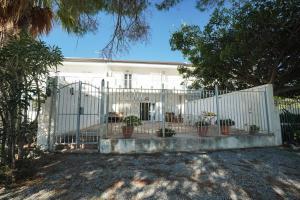 a white fence in front of a house with potted plants at Max in Condofuri